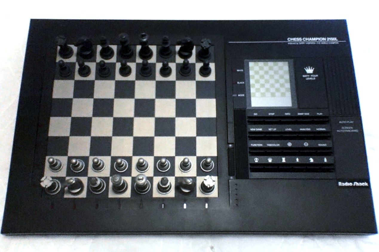 A dedicated tabletop chess computer with a sensory board, chess pieces, a small display, and control buttons, illustrating the self-contained format
